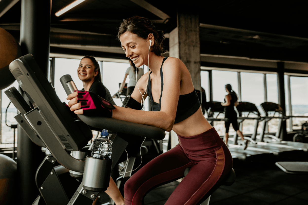 Sportlerinnen trainieren auf Cardio-Geraeten in einem Fitnessstudio