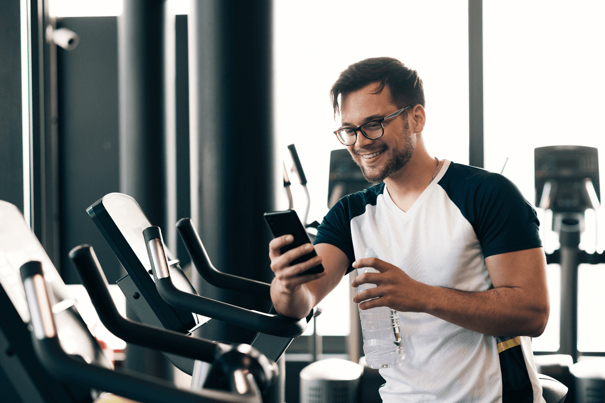 Sportler prüft Trainingsübersicht auf dem Smartphone im Studio
