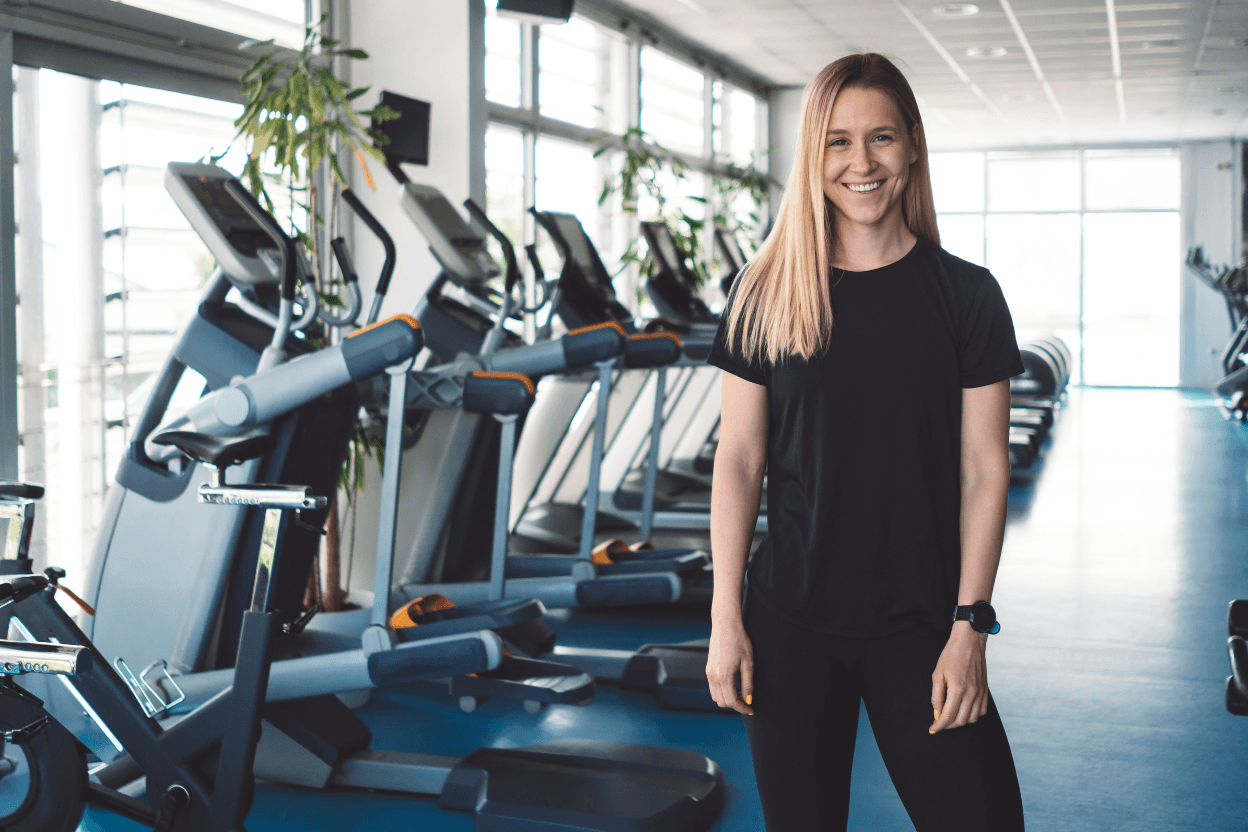 Sportlerin steht in einem Fitnessstudio vor Trainingsgeraeten